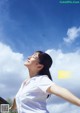 A woman in a white shirt is looking up at the sky.