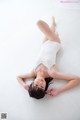 A woman in a white leotard laying on the floor.