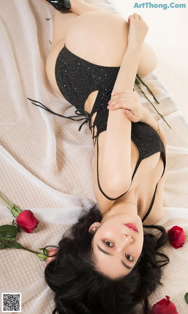 A woman laying on a bed with a rose in her hand.