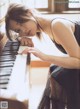 A woman in a black dress sitting at a piano.