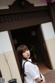 A woman standing in front of a building wearing a white shirt.