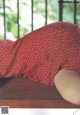 A woman in a red polka dot dress laying on a wooden table.