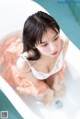 A woman sitting in a bathtub with her feet in the water.