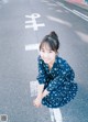 A woman in a blue dress crouching down on the street.