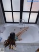 A woman laying in a bathtub with her feet up in the air.