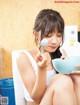 A woman sitting on a chair holding a spoon and a bowl.