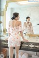 A woman standing in front of a mirror in a bathroom.