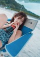 A woman sitting in a beach chair drinking from a bottle.