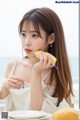 A woman sitting at a table eating a piece of fruit.