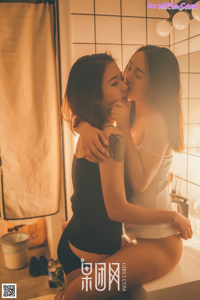 A couple of women sitting on top of a bathtub.